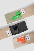 Top view of the shoulder strap pockets on the pet sling carrier, holding a smartphone and small snack packs, showing built-in storage along the strap.