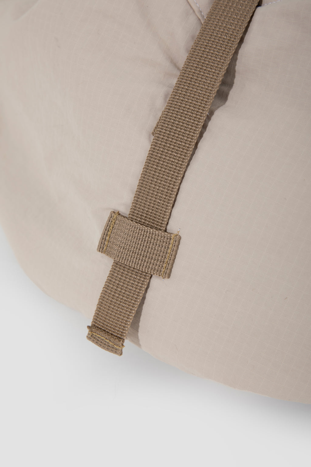Detail view of the external support strap on the pet sling carrier, showing the stitched webbing that helps hold the bag shape in place.
