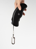 Hand holding a retractable dog leash with a metal clip hanging down
