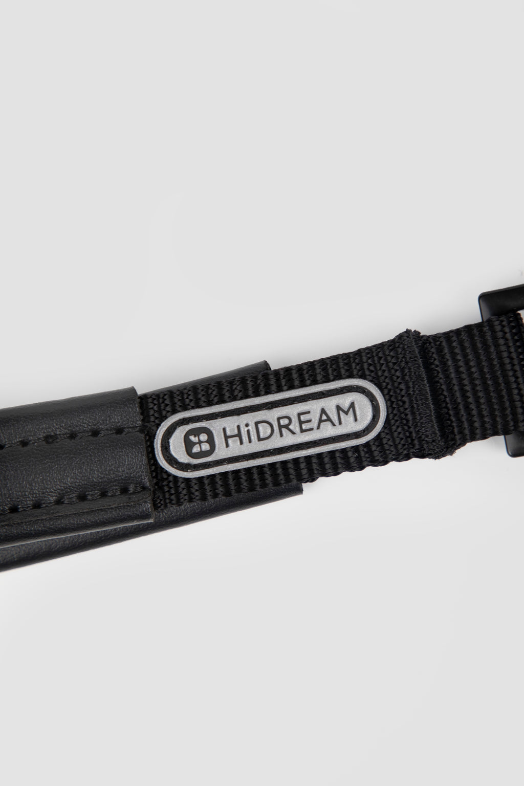 Close-up of brand logo patch on black webbing of a slip dog leash, showing woven nylon detail and stitched finish.