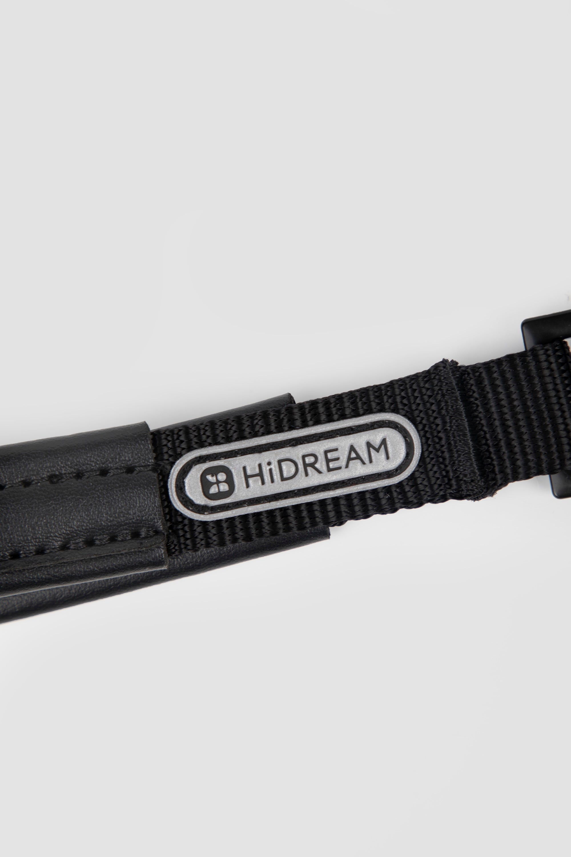 Close-up of brand logo patch on black webbing of a slip dog leash, showing woven nylon detail and stitched finish.