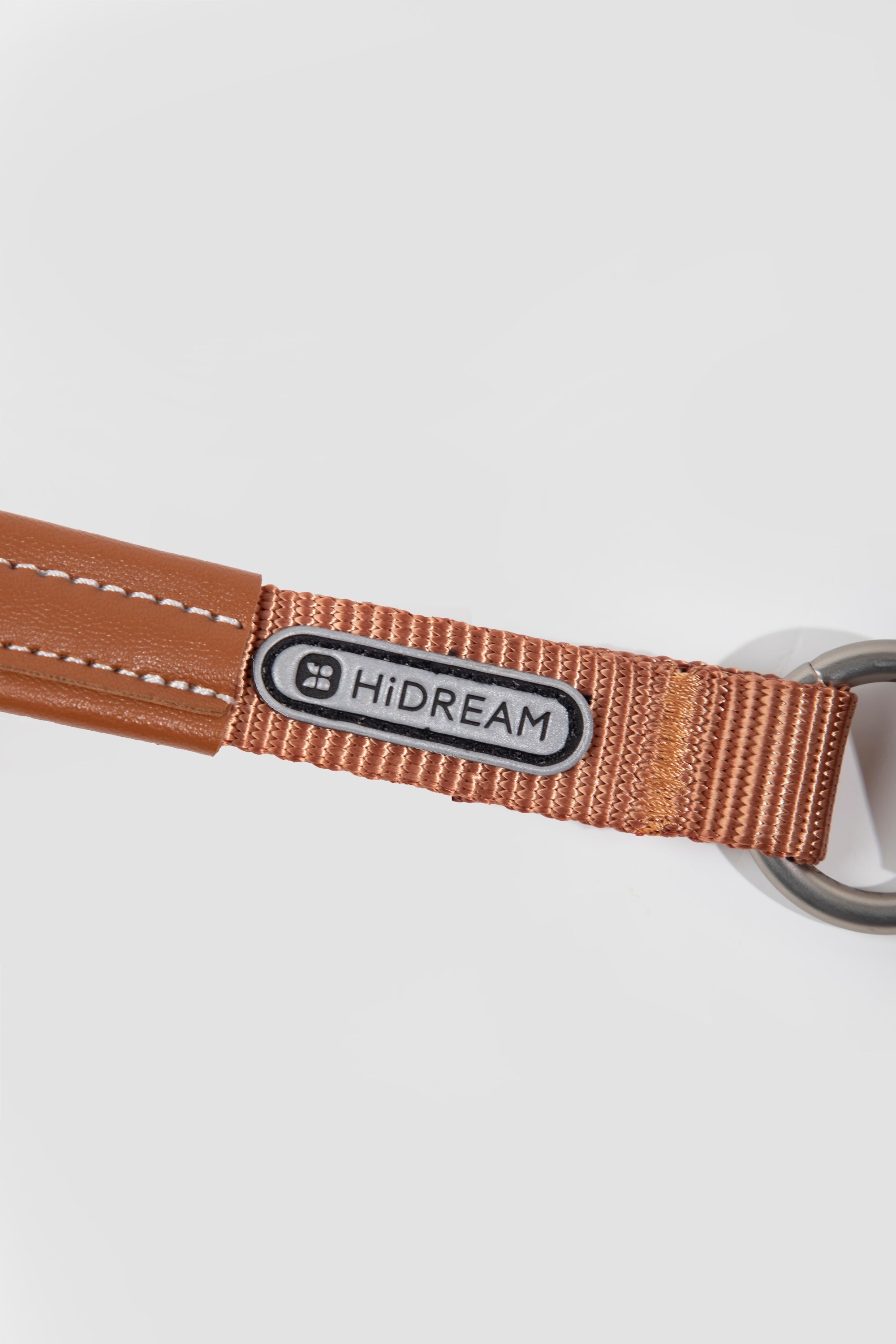 Close-up of brand logo patch on brown webbing of a slip dog leash, highlighting nylon texture and clean stitching.