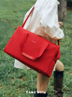 Person carrying a red stealth pet carrier bag over the shoulder while walking outdoors on grass