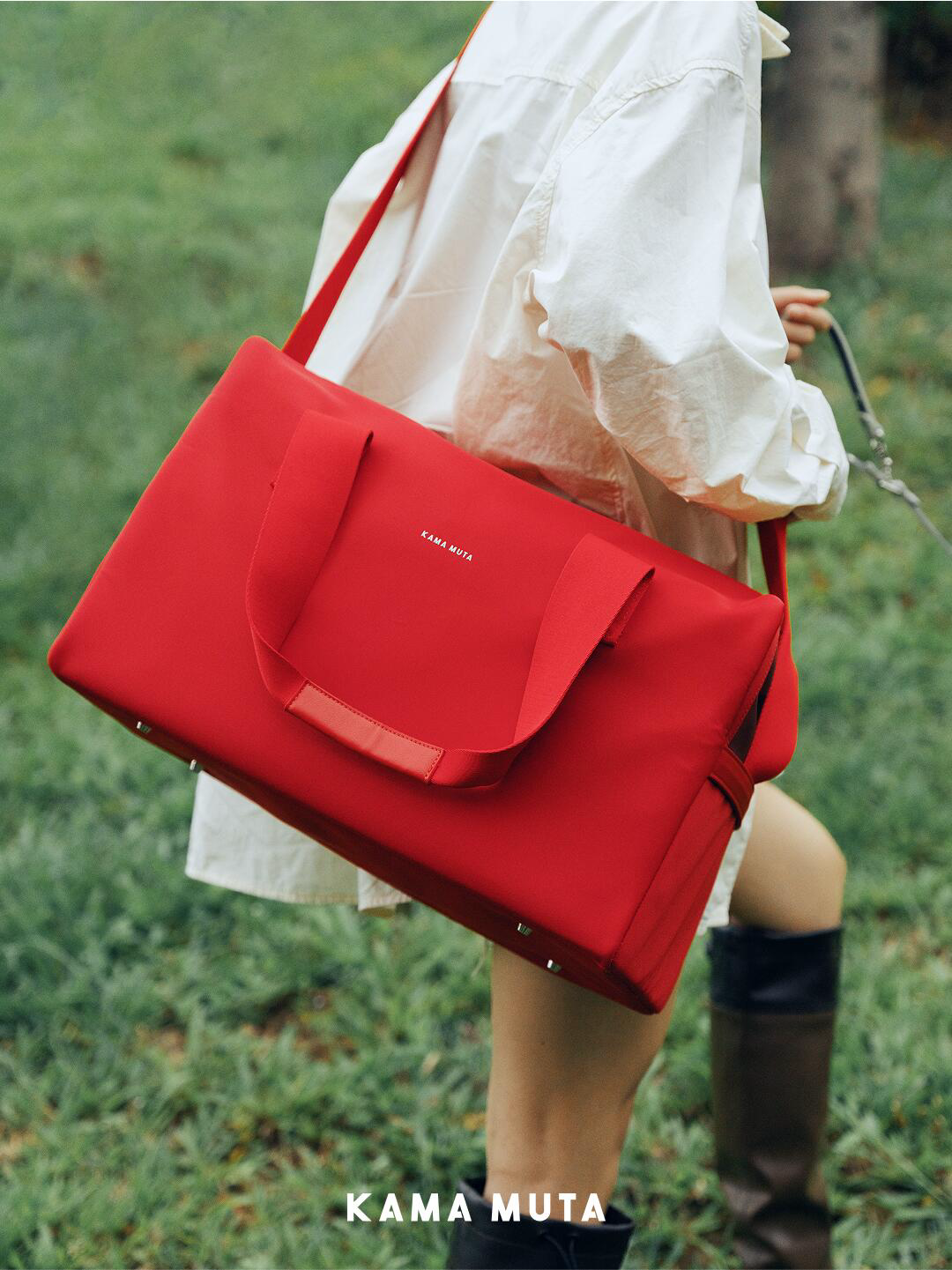 Person carrying a red stealth pet carrier bag over the shoulder while walking outdoors on grass