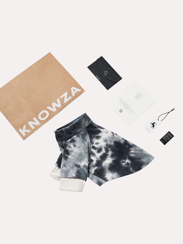 Flat lay of a tie dye corduroy dog shirt with packaging, showing fabric pattern, collar shape, and relaxed cut