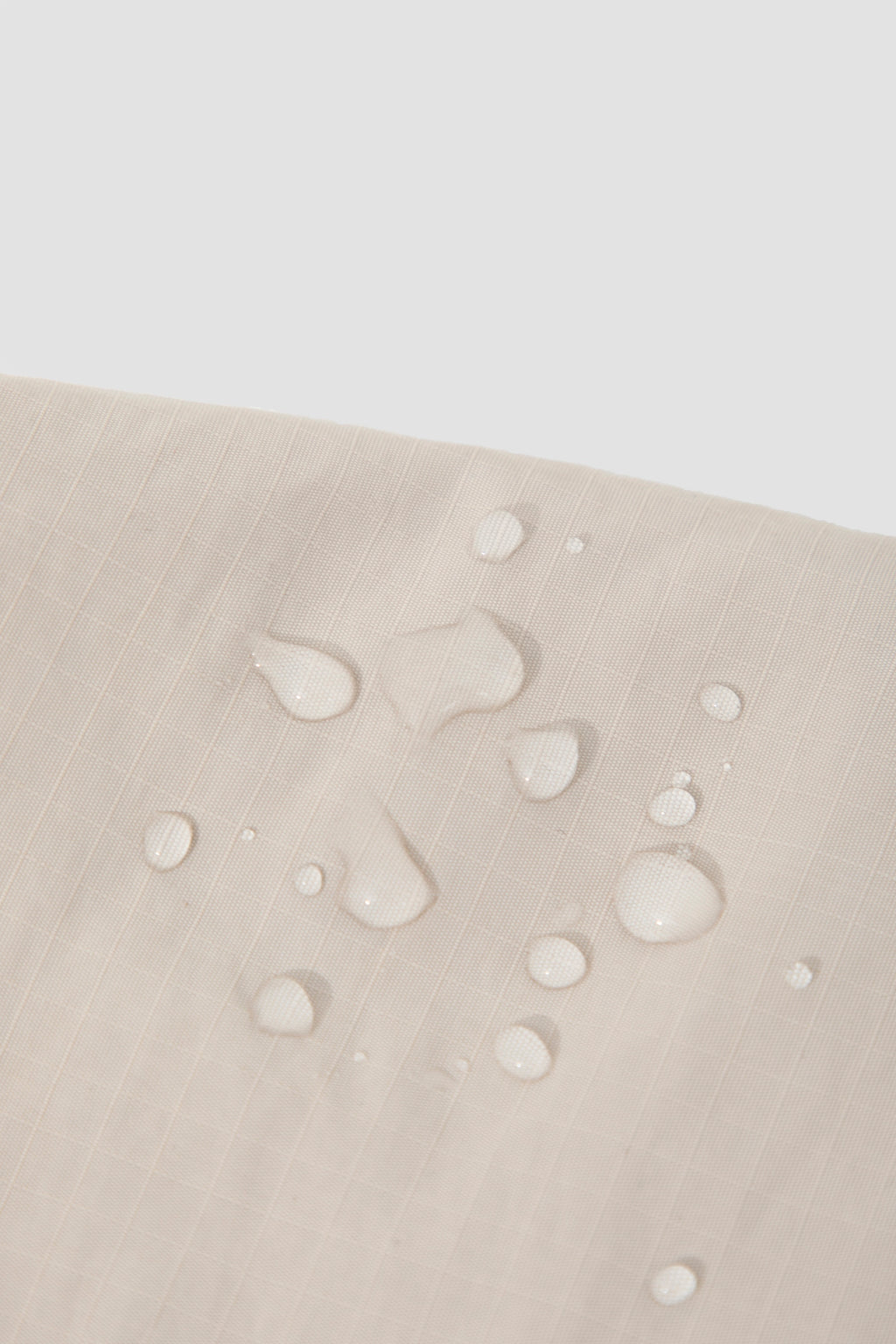 Close-up of water droplets on the nylon fabric of a dog treat pouch, showing the water-resistant surface and fabric texture.