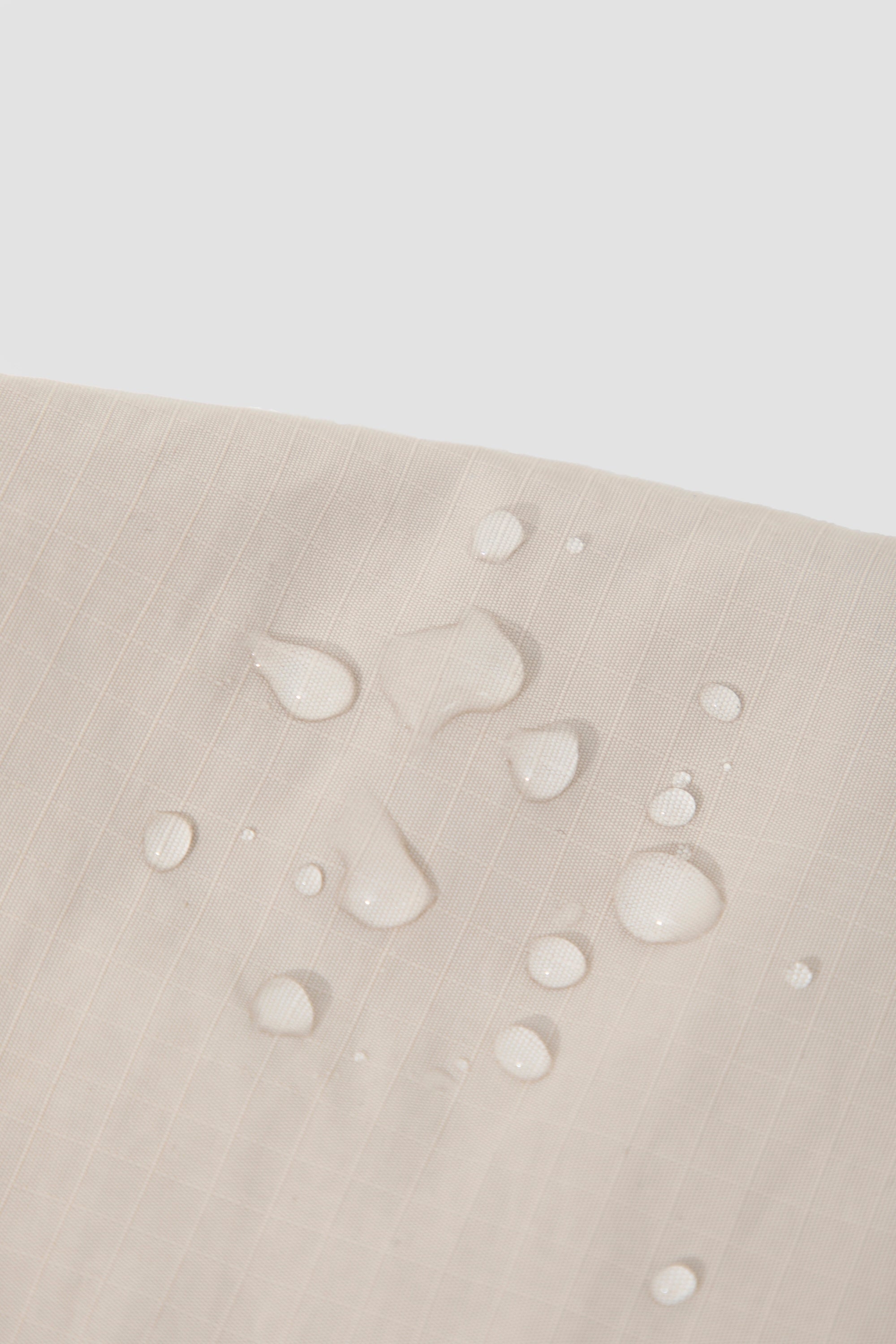 Close-up of water droplets on the nylon fabric of a dog treat pouch, showing the water-resistant surface and fabric texture.