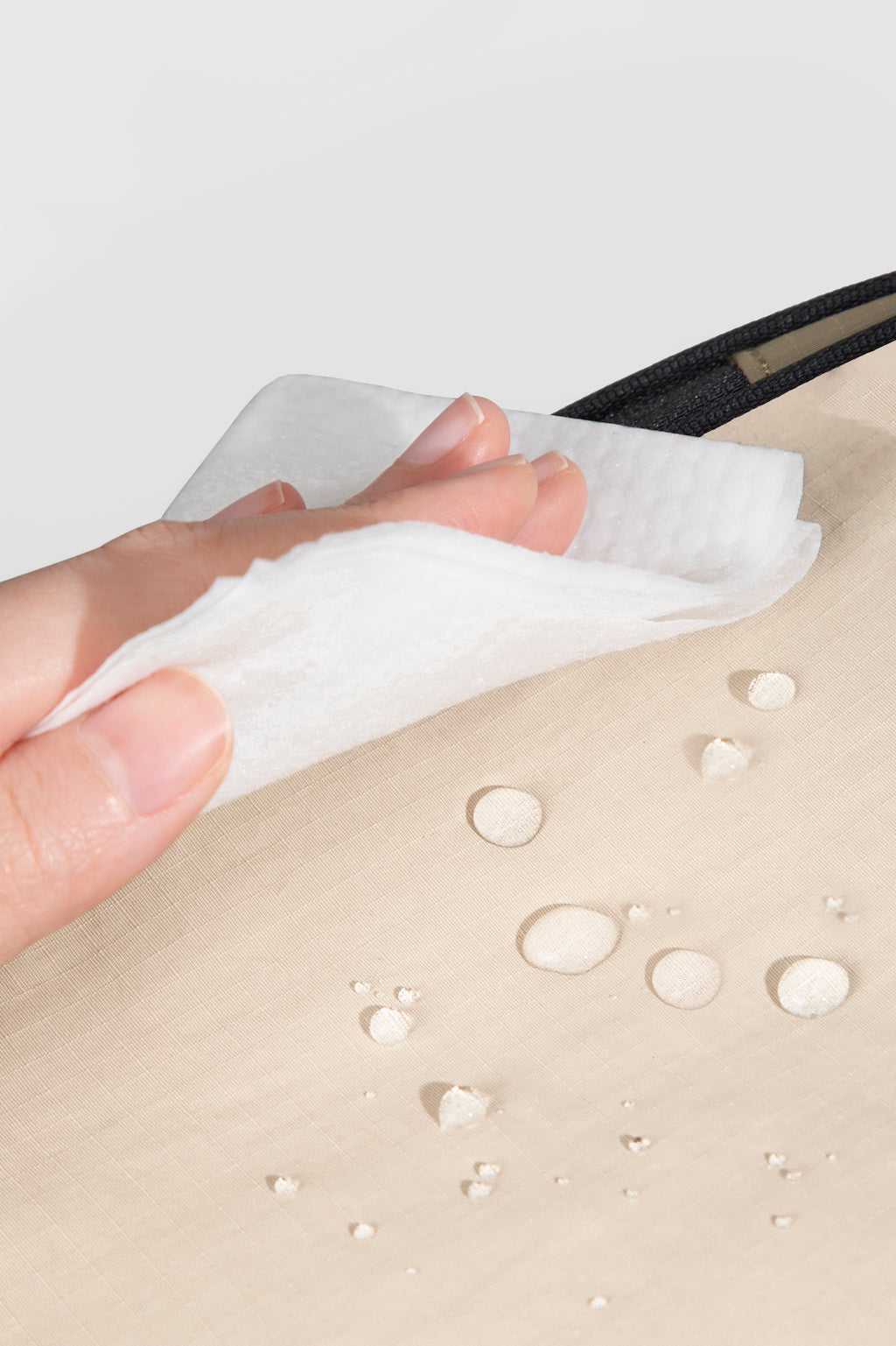 Close-up of water-resistant nylon fabric on a front pet carrier, showing easy-clean surface with moisture beading