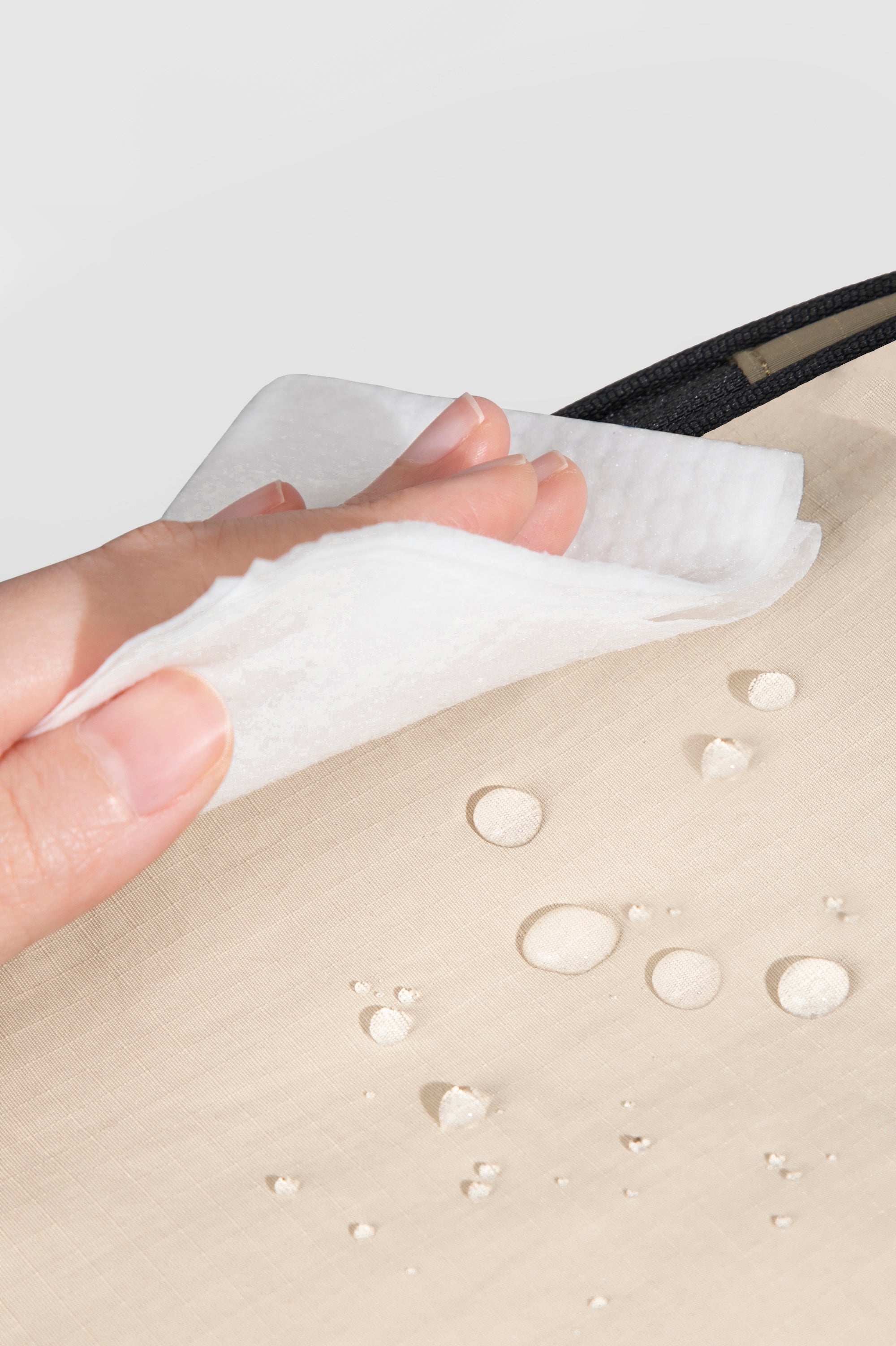 Close-up of water-resistant nylon fabric on a front pet carrier, showing easy-clean surface with moisture beading