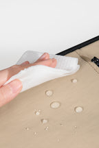  Close-up of water droplets on the pet carrier backpack fabric being wiped with a cloth, showing water-resistant material and easy cleaning.