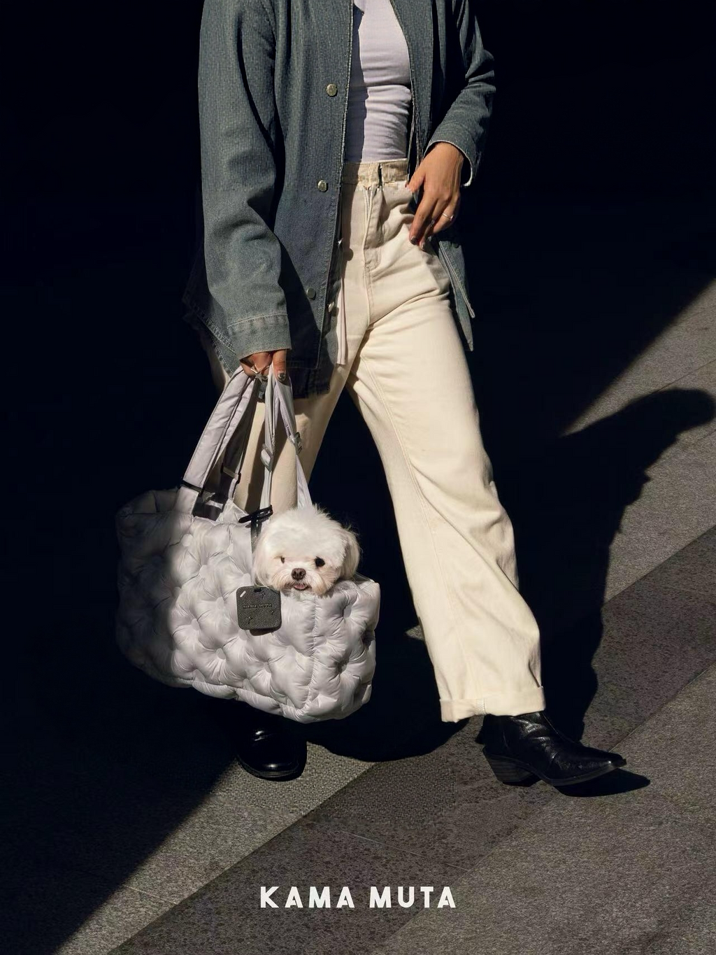 White padded dog carrier bag carried by hand, designed for warm and lightweight travel with small dogs.